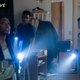 A young woman holds a flashlight in the foreground, along with two young men who are also holding flashlights.